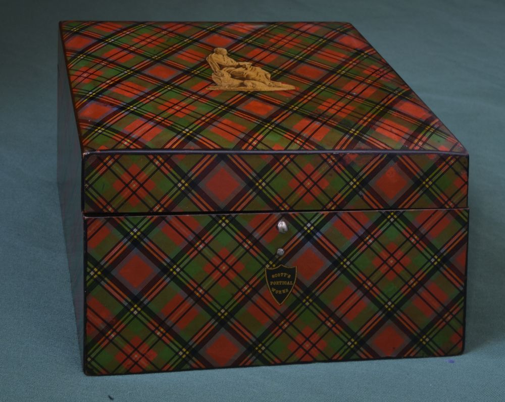 Square enamelled effect box with tartan pattern in red, black and green. Yellow image of Sir Walter Scott on the lid