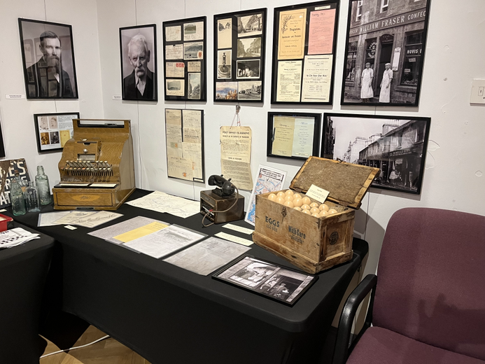 Image of the exhibition. A till on a table alonge with photographs on the wall